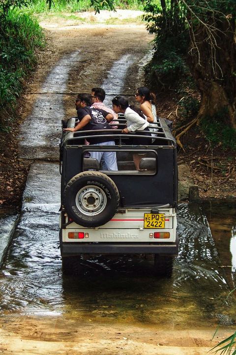 A safari jeep full of travellers crossing a stream